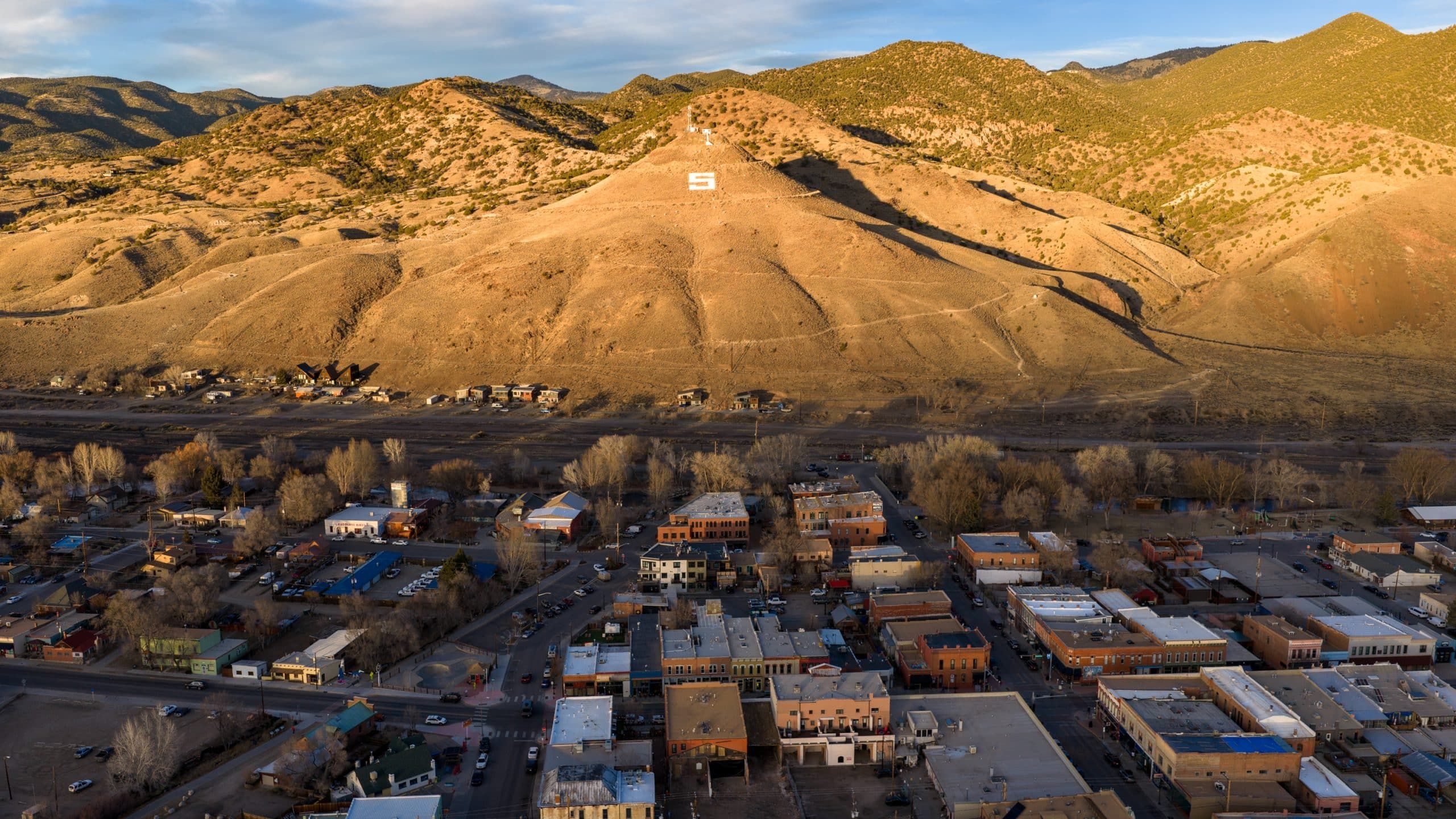 Small town beneath hillside with large white S