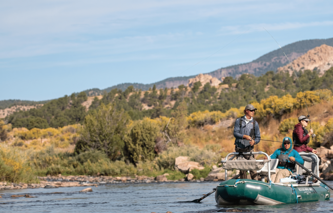 People fly fishing from raft on scenic river