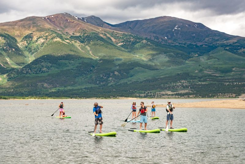 Group paddleboarding on mountain lake under cloudy sky