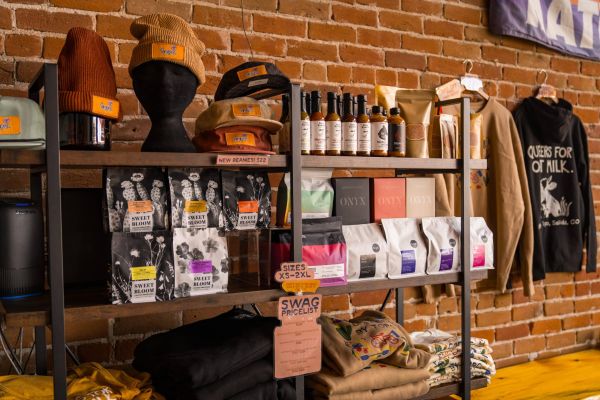 Coffee shop merchandise shelf with beanies, sauces, coffee, and shirts