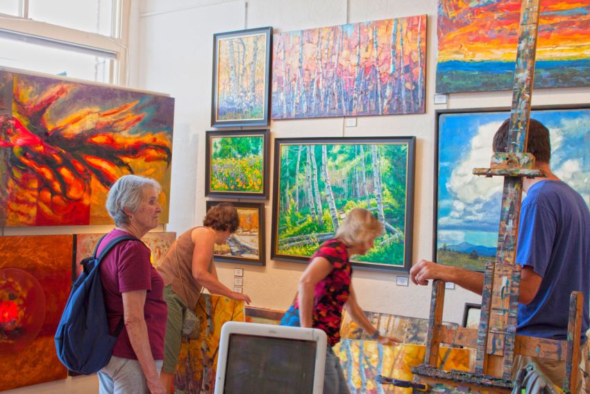 Four people enjoying some colorful paintings in an art gallery