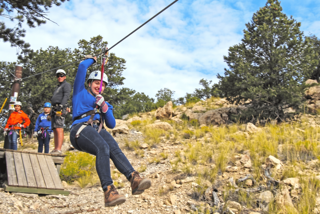 Woman ziplining over rocky hillside with helmet