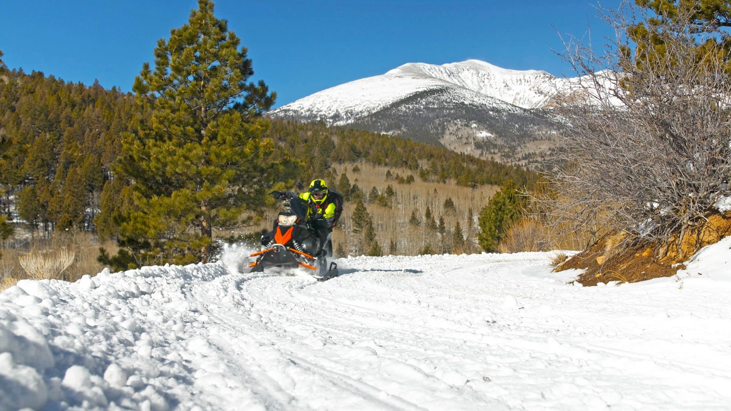 Snowmobiler riding on snowy mountain trail