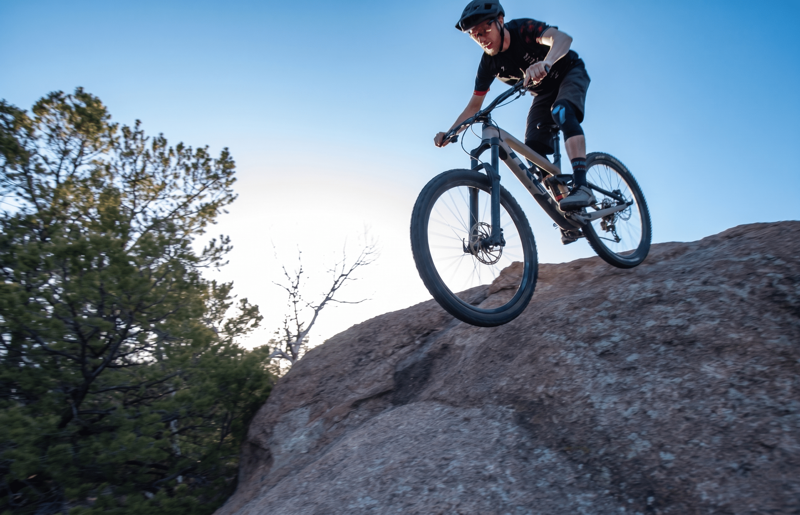 Mountain biker descending rocky trail at sunset