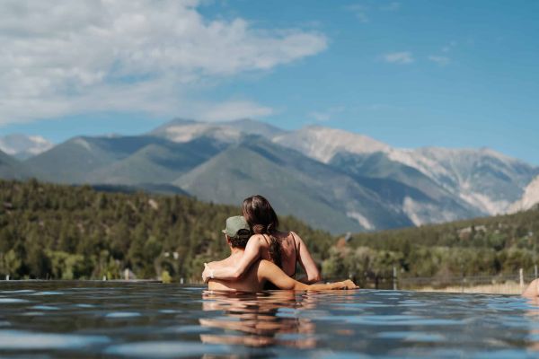 Couple embraces in pool overlooking forested mountains