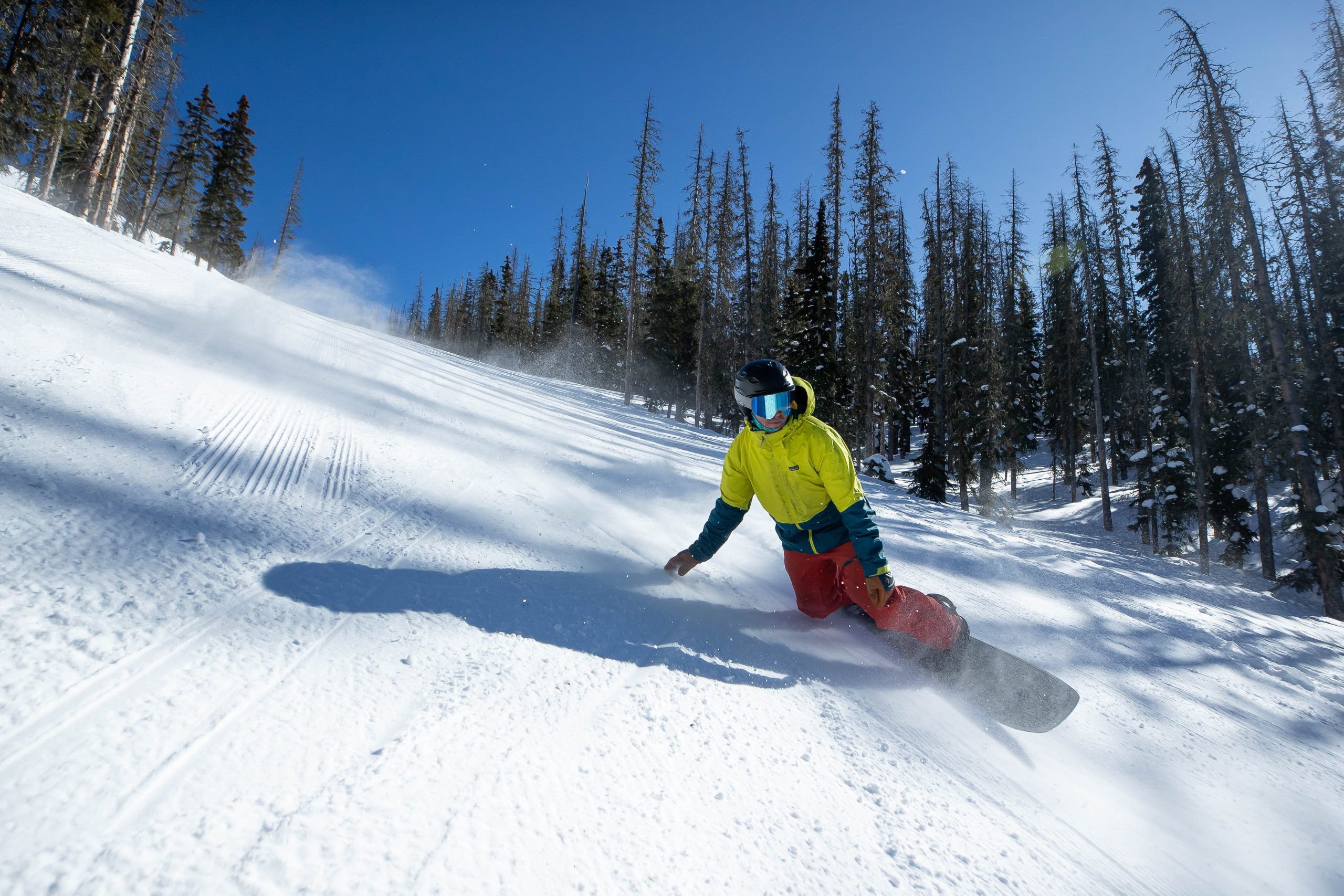 Snowboarder carving down snowy mountain slope.