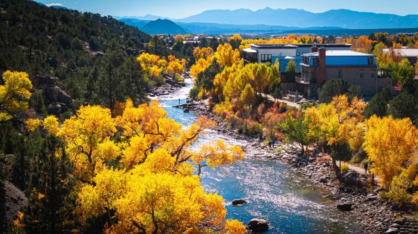 Autumn river winding through colorful trees beneath mountains