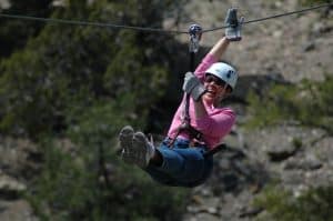 Woman ziplining over forested canyon