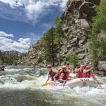 Group whitewater rafting through rocky canyon river