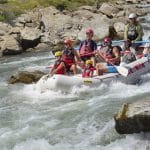 Family whitewater rafting through rocky river rapids