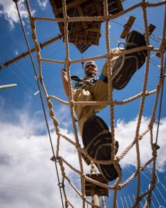 Man climbing rope net on outdoor obstacle course