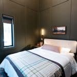 Modern bedroom with dark paneled walls and mirror