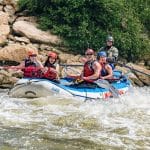 Group whitewater rafting through rocky river rapids