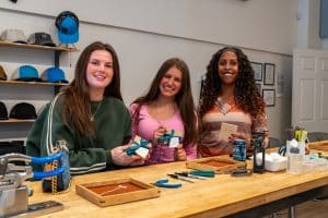Three women holding gift boxes in workshop