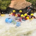 Whitewater rafting group navigating rocky river rapids