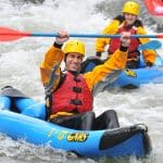 Two men whitewater rafting in inflatable kayaks