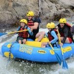 Family whitewater rafting through rocky canyon rapids