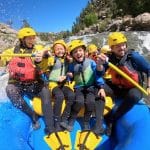 Family white-water rafting through rocky river rapids